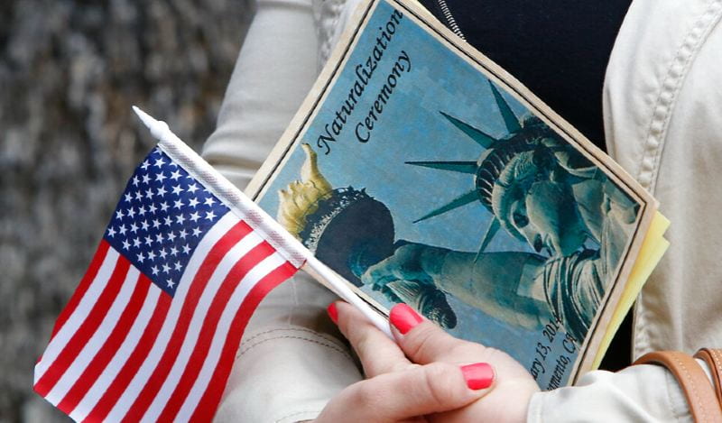 A woman holding an American flag and a Naturalization Ceremony pamphlet