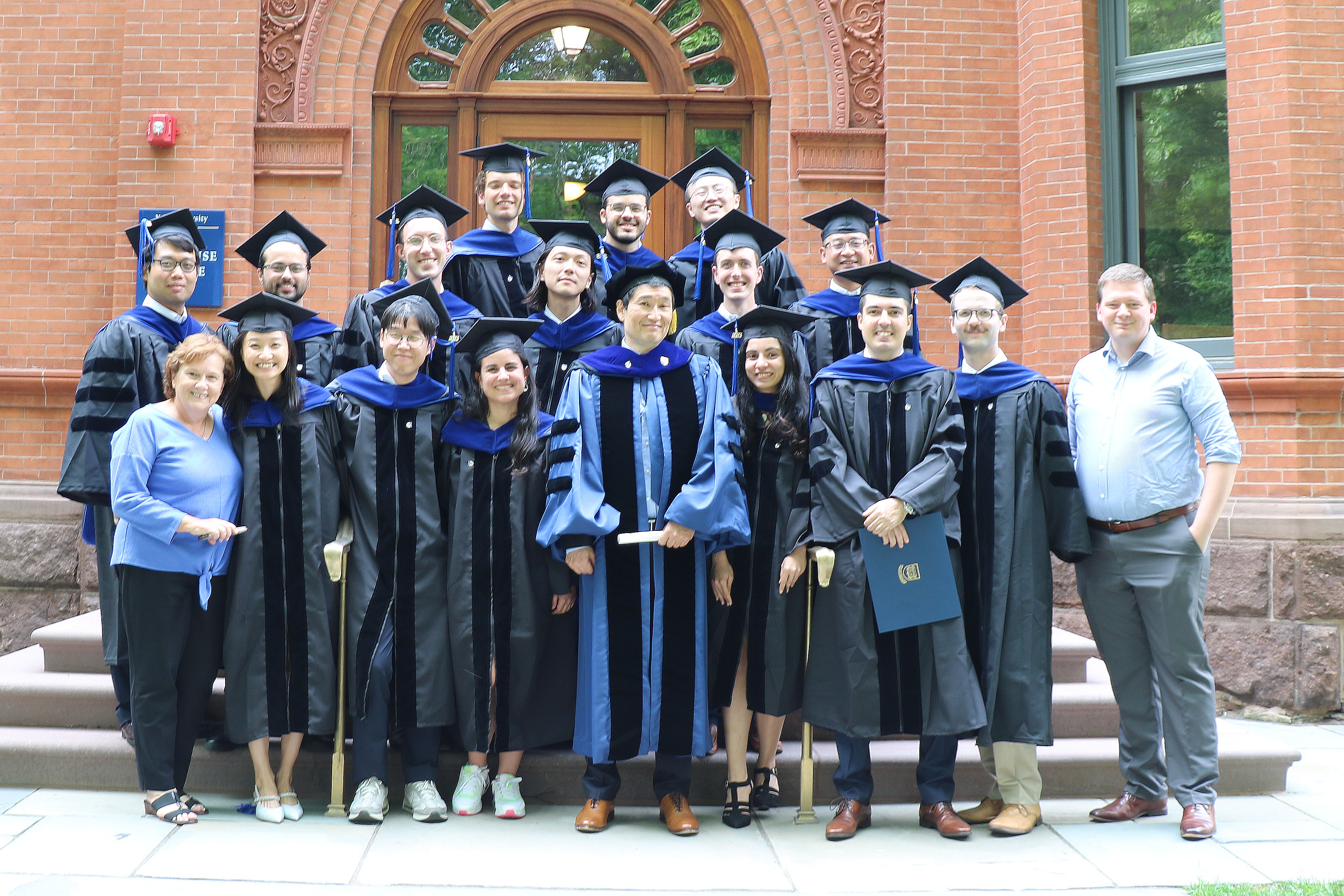 the Economics PhD Class of 2023 standing outside 28 Hillhouse Ave with Graduate Registrars Pam O'Donnell and Scott Runner, and Director of Graduate Studies Yuichi Kitamura